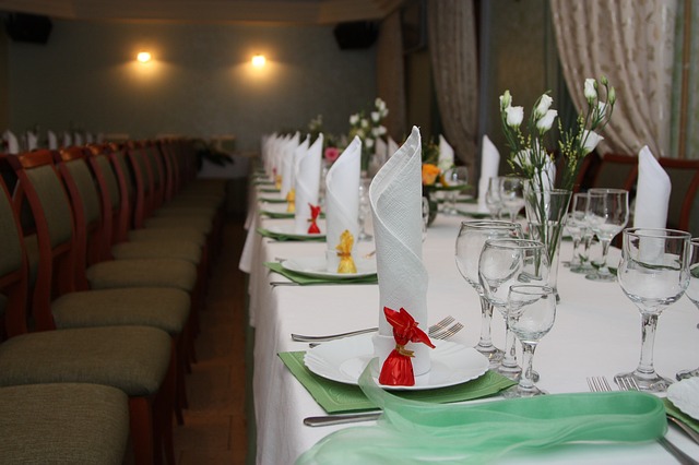 prostřený stůl na svatbu, ubrousky na stojku, zelené ubrousky, sklenice, mnoho židlí